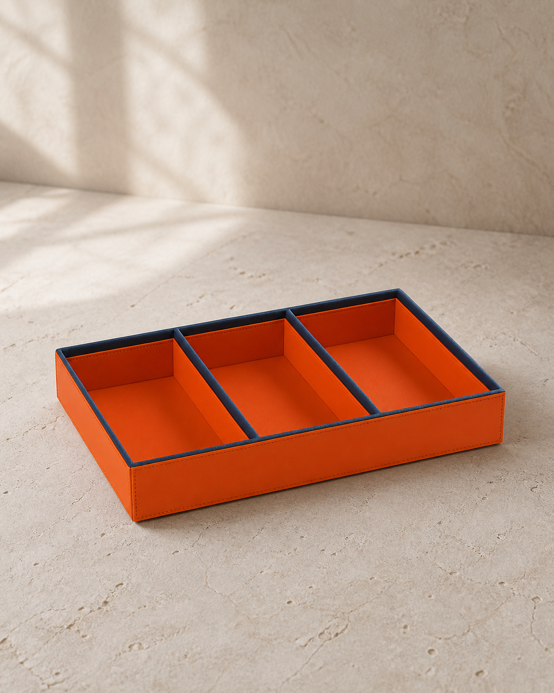 Orange compartment tray with blue piping, 3 compartments, grounded editorial view